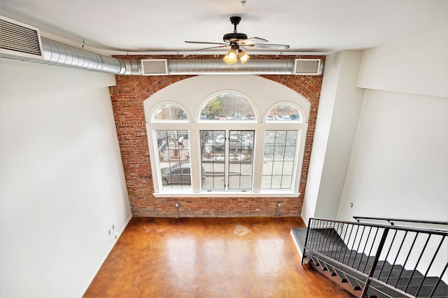 empty room with hardwood / wood-style flooring, ceiling fan, and brick wall