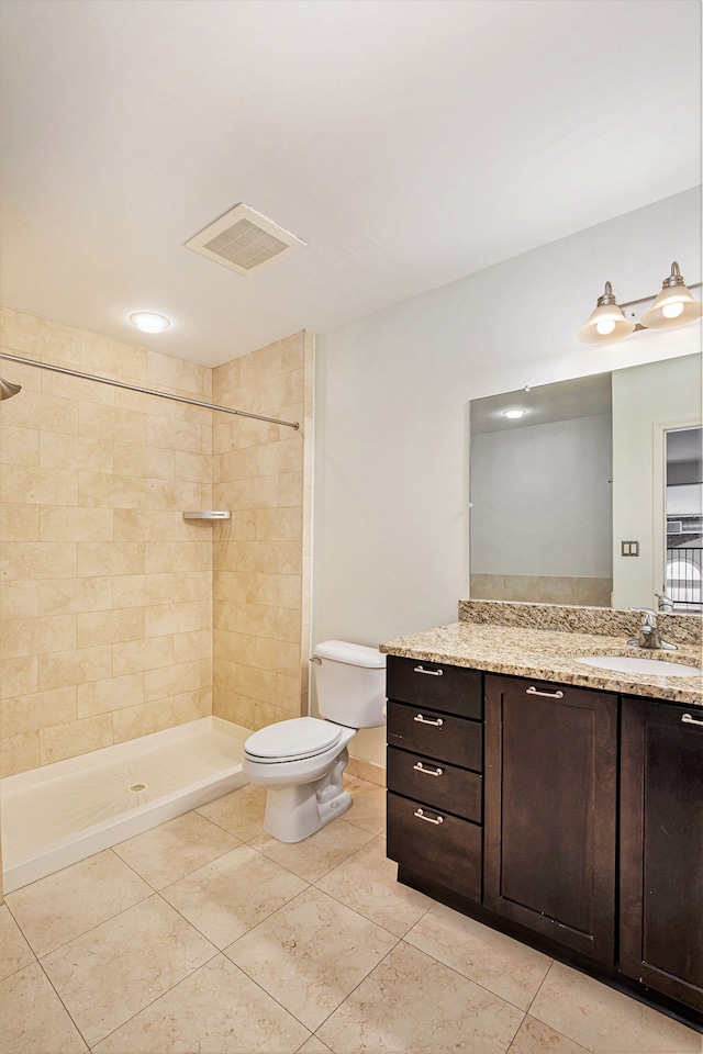 bathroom featuring tile patterned flooring, vanity, tiled shower, and toilet