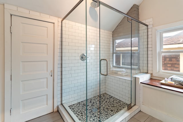 bathroom featuring tile patterned flooring, vaulted ceiling, and walk in shower