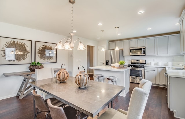 dining room with dark wood-type flooring, sink, and a notable chandelier