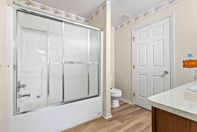 full bathroom featuring vanity, wood-type flooring, shower / bath combination with glass door, and toilet