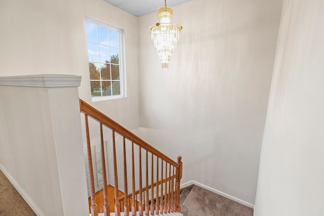 stairs with a chandelier and carpet