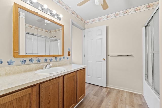 bathroom featuring vanity, hardwood / wood-style floors, bath / shower combo with glass door, and ceiling fan