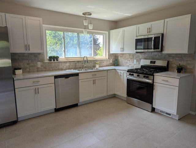 kitchen with appliances with stainless steel finishes, decorative light fixtures, sink, white cabinets, and decorative backsplash