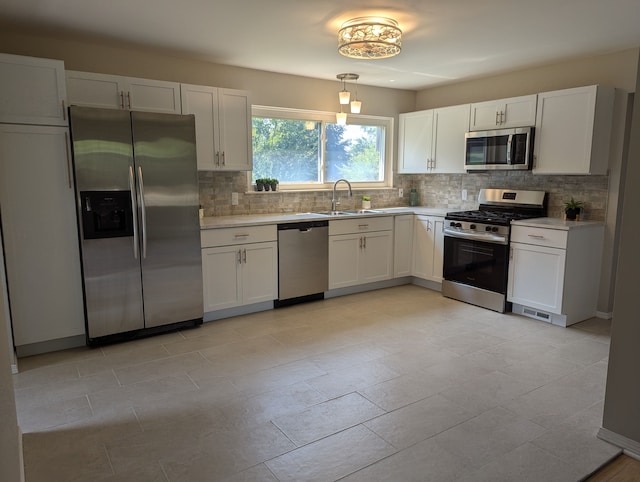 kitchen with sink, appliances with stainless steel finishes, tasteful backsplash, white cabinets, and decorative light fixtures