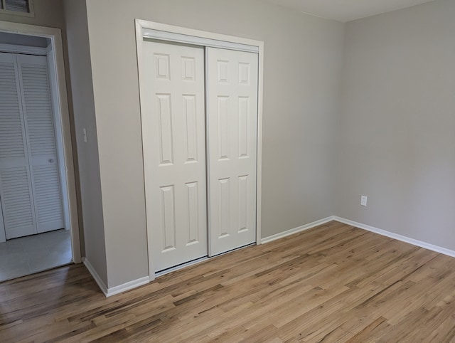 unfurnished bedroom featuring light hardwood / wood-style flooring and a closet