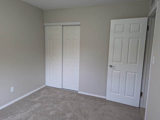 unfurnished bedroom with light carpet and a closet