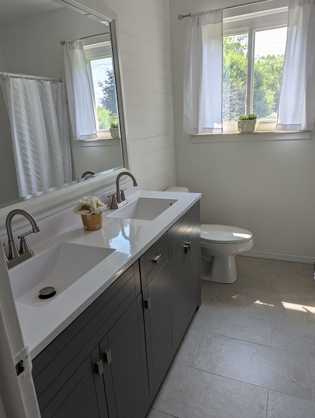 bathroom featuring vanity, a healthy amount of sunlight, tile patterned floors, and toilet