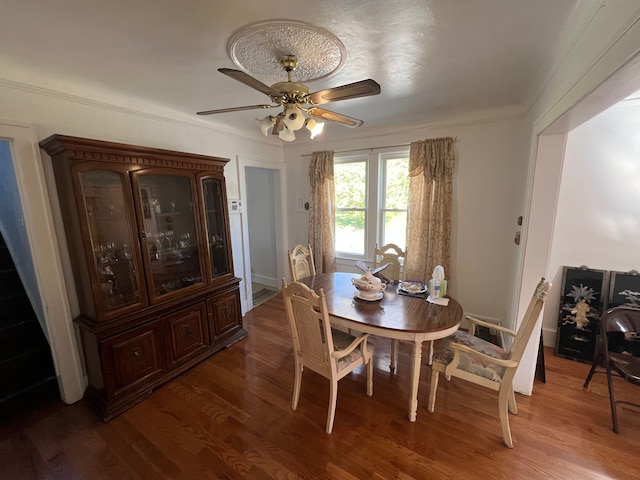 dining area featuring dark wood-type flooring, ornamental molding, and ceiling fan