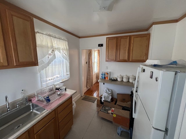 kitchen featuring ornamental molding, sink, light tile patterned floors, and refrigerator