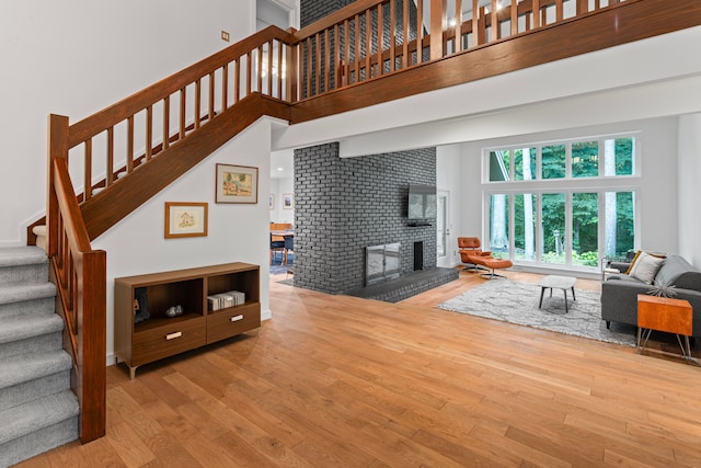 living room featuring a high ceiling, a brick fireplace, and hardwood / wood-style flooring