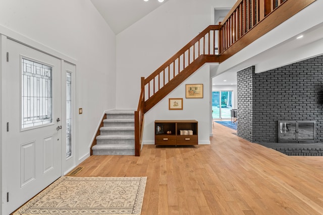 foyer featuring a fireplace, high vaulted ceiling, and light hardwood / wood-style flooring