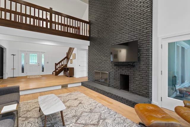 living room with hardwood / wood-style floors, a towering ceiling, and a fireplace