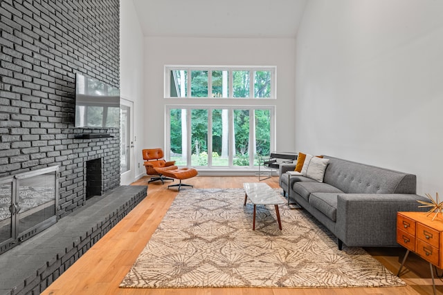 living room with a fireplace, high vaulted ceiling, and hardwood / wood-style floors