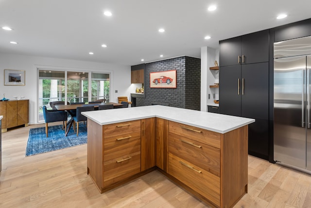 kitchen featuring built in refrigerator, a kitchen island, and light wood-type flooring