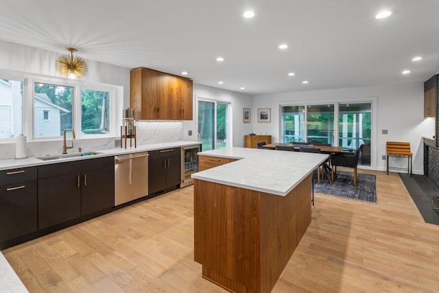 kitchen featuring a kitchen island, sink, wine cooler, stainless steel dishwasher, and light hardwood / wood-style flooring