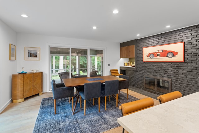 dining space featuring a brick fireplace and light wood-type flooring