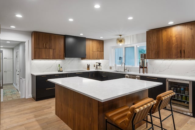 kitchen featuring wine cooler, a kitchen bar, sink, a kitchen island, and black electric stovetop