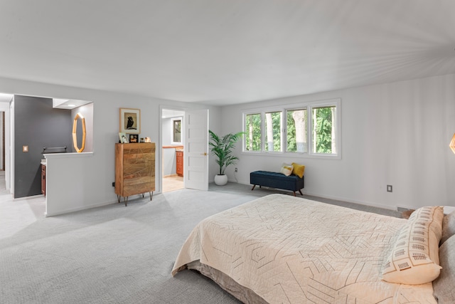 bedroom featuring ensuite bathroom and light carpet