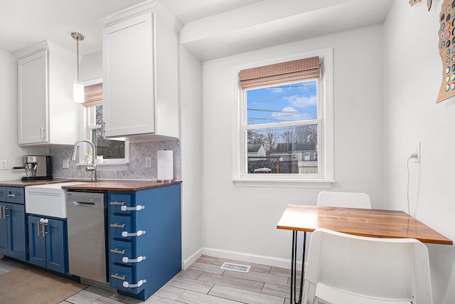 kitchen featuring tasteful backsplash, white cabinets, hanging light fixtures, stainless steel dishwasher, and blue cabinetry