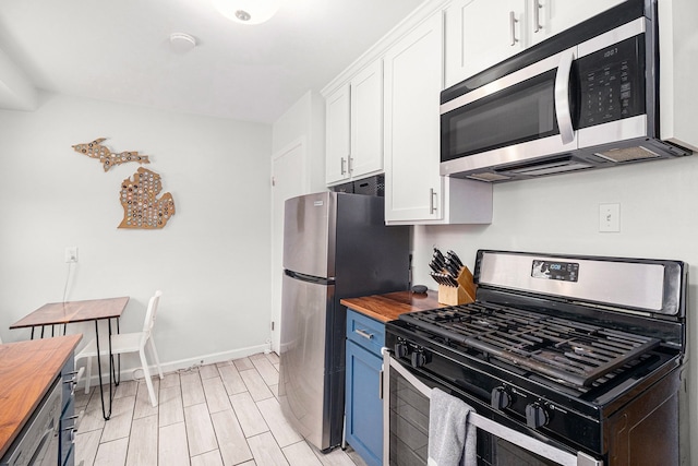 kitchen featuring white cabinetry, stainless steel appliances, wooden counters, and blue cabinets