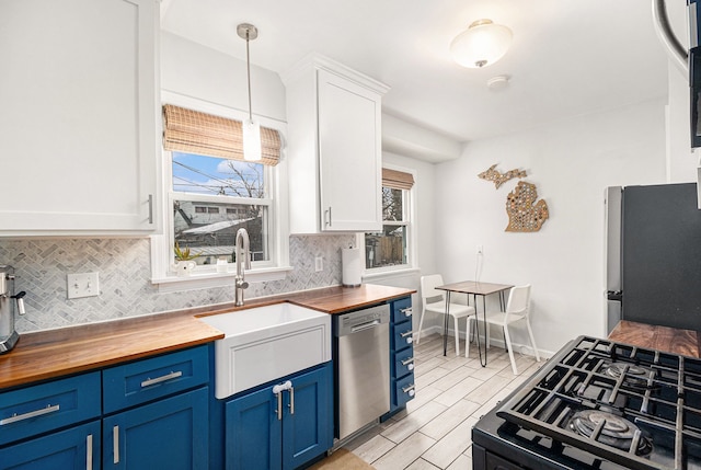 kitchen featuring butcher block countertops, stainless steel appliances, hanging light fixtures, and white cabinets