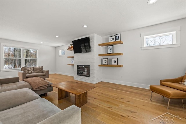 living room featuring a brick fireplace and light hardwood / wood-style floors