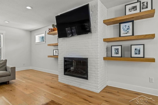 living room featuring a textured ceiling, a fireplace, and wood-type flooring