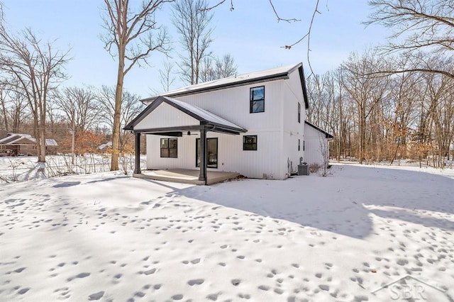 snow covered house with a porch and central air condition unit