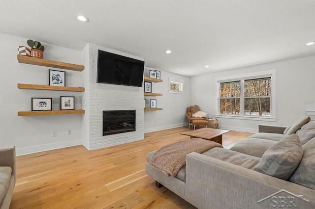 living room with wood-type flooring and a brick fireplace