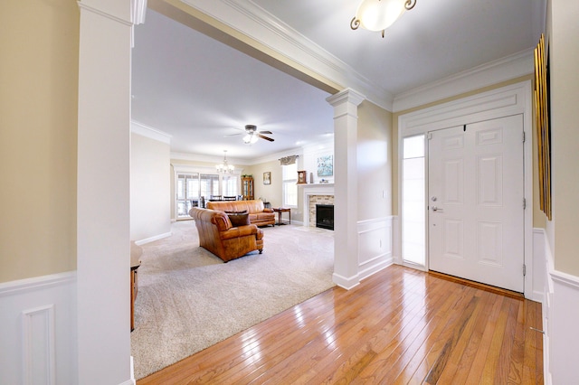 entryway with crown molding, ceiling fan with notable chandelier, light hardwood / wood-style floors, and ornate columns