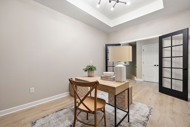 office space featuring a tray ceiling and light wood-type flooring