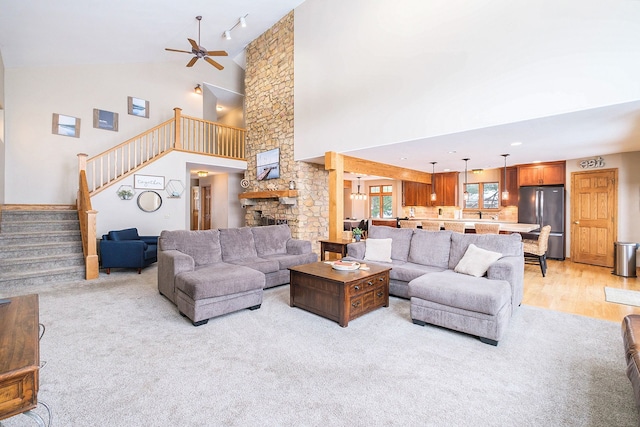 living room with a stone fireplace, high vaulted ceiling, and ceiling fan