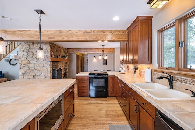 kitchen with sink, stove, stainless steel microwave, tile countertops, and light wood-type flooring