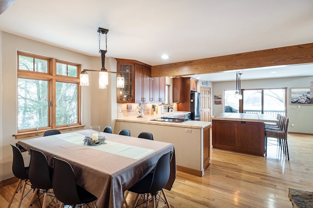 dining area with beam ceiling and light hardwood / wood-style flooring