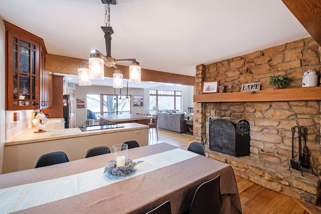 dining space featuring a stone fireplace and light wood-type flooring