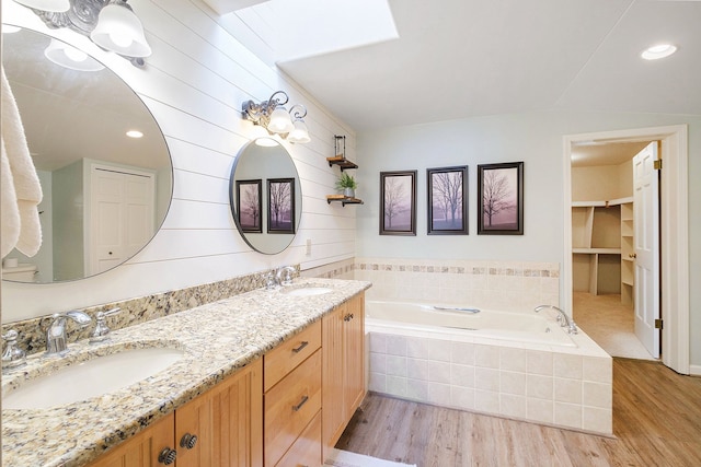 bathroom with vanity, hardwood / wood-style floors, and tiled tub