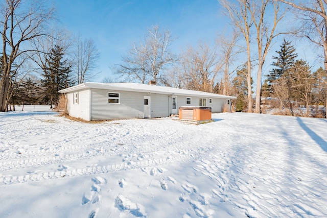 snow covered property with a hot tub