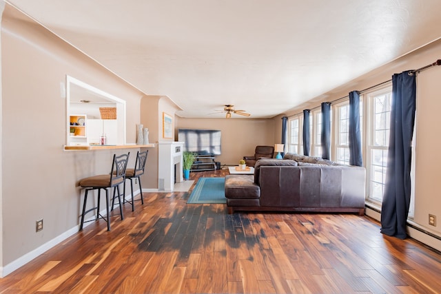 living room featuring a baseboard heating unit, dark wood-type flooring, and ceiling fan