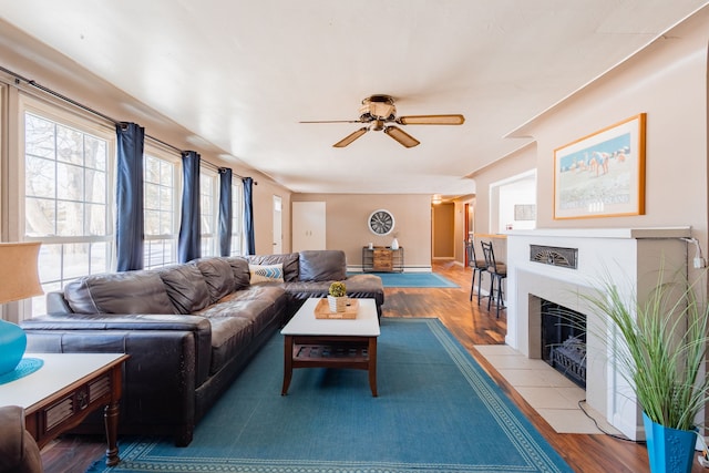 living room featuring ceiling fan, a fireplace, and light hardwood / wood-style floors