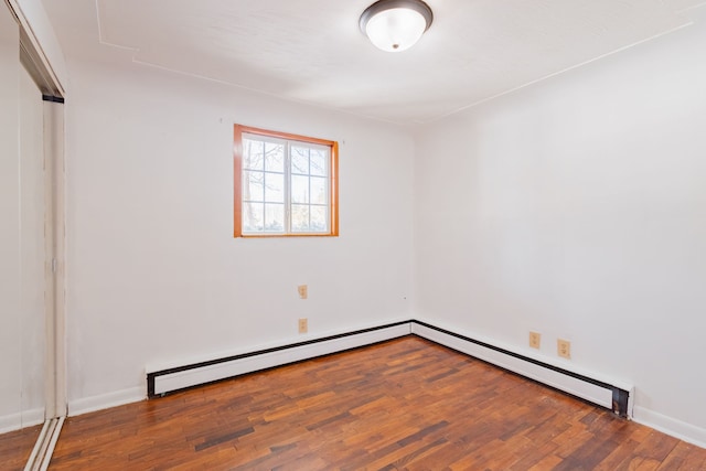 empty room with wood-type flooring and a baseboard heating unit