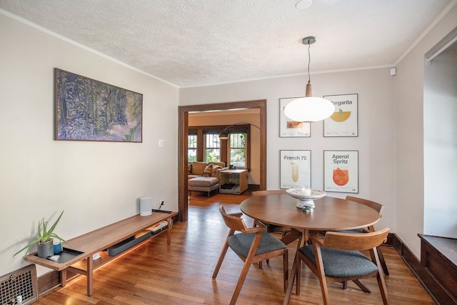 dining space with ornamental molding, hardwood / wood-style floors, and a textured ceiling