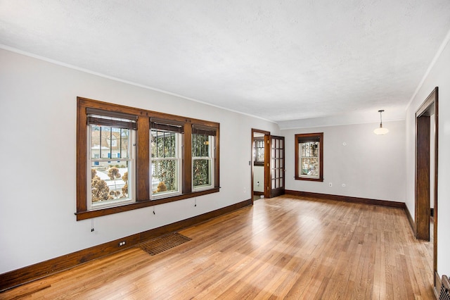 unfurnished room featuring ornamental molding, a textured ceiling, and light wood-type flooring