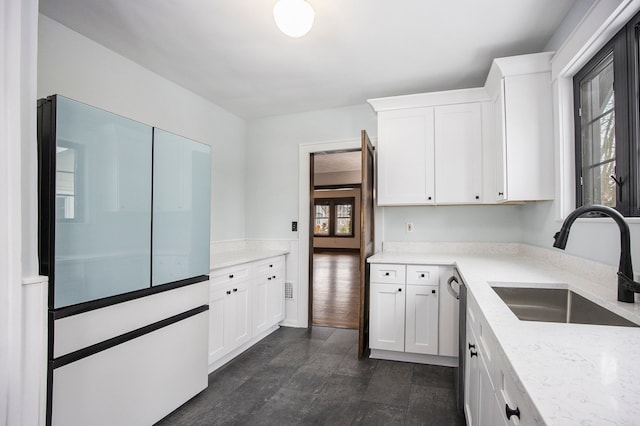 kitchen with light stone counters, dishwasher, sink, and white cabinets