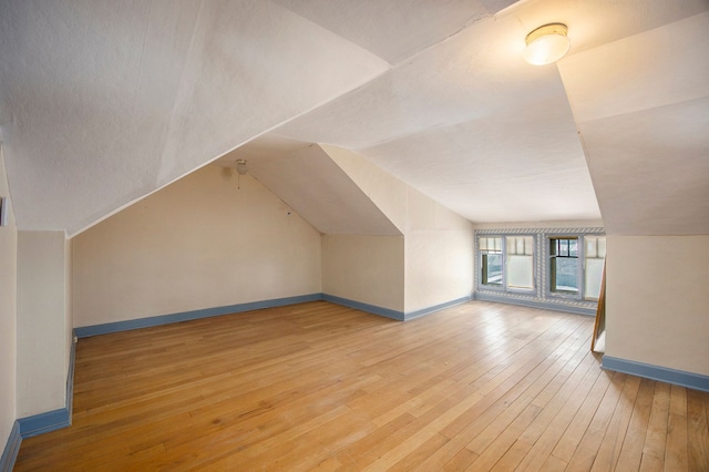 additional living space featuring light hardwood / wood-style flooring and vaulted ceiling