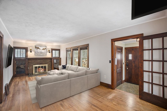 living room with crown molding, a fireplace, light hardwood / wood-style flooring, and a textured ceiling