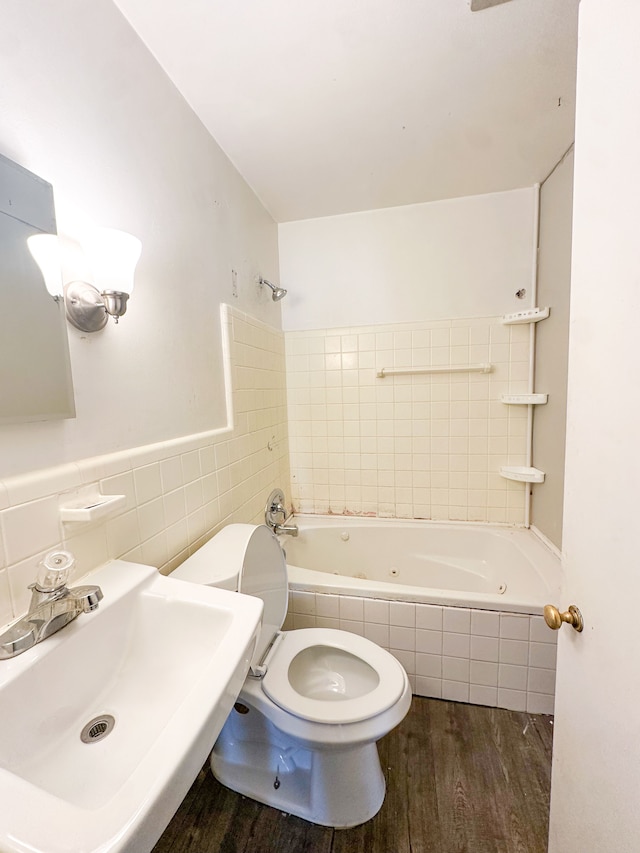 full bathroom with tiled shower / bath, sink, tile walls, hardwood / wood-style flooring, and toilet