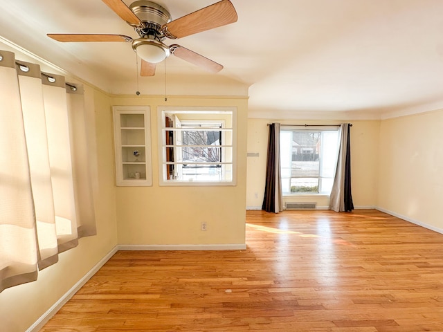 unfurnished room with built in shelves, ceiling fan, and light wood-type flooring