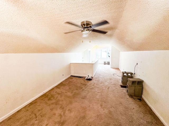 additional living space with light carpet, ceiling fan, vaulted ceiling, and a textured ceiling