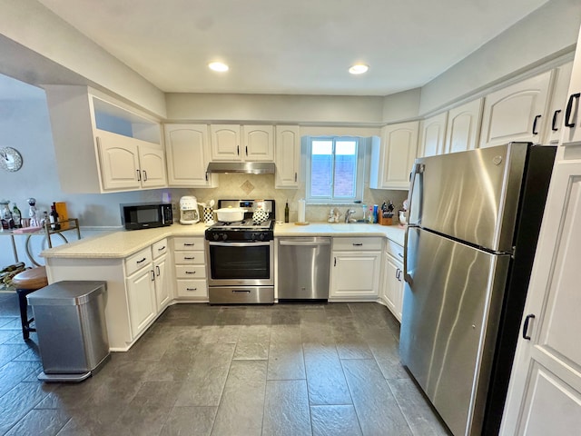 kitchen with backsplash, stainless steel appliances, kitchen peninsula, and white cabinets